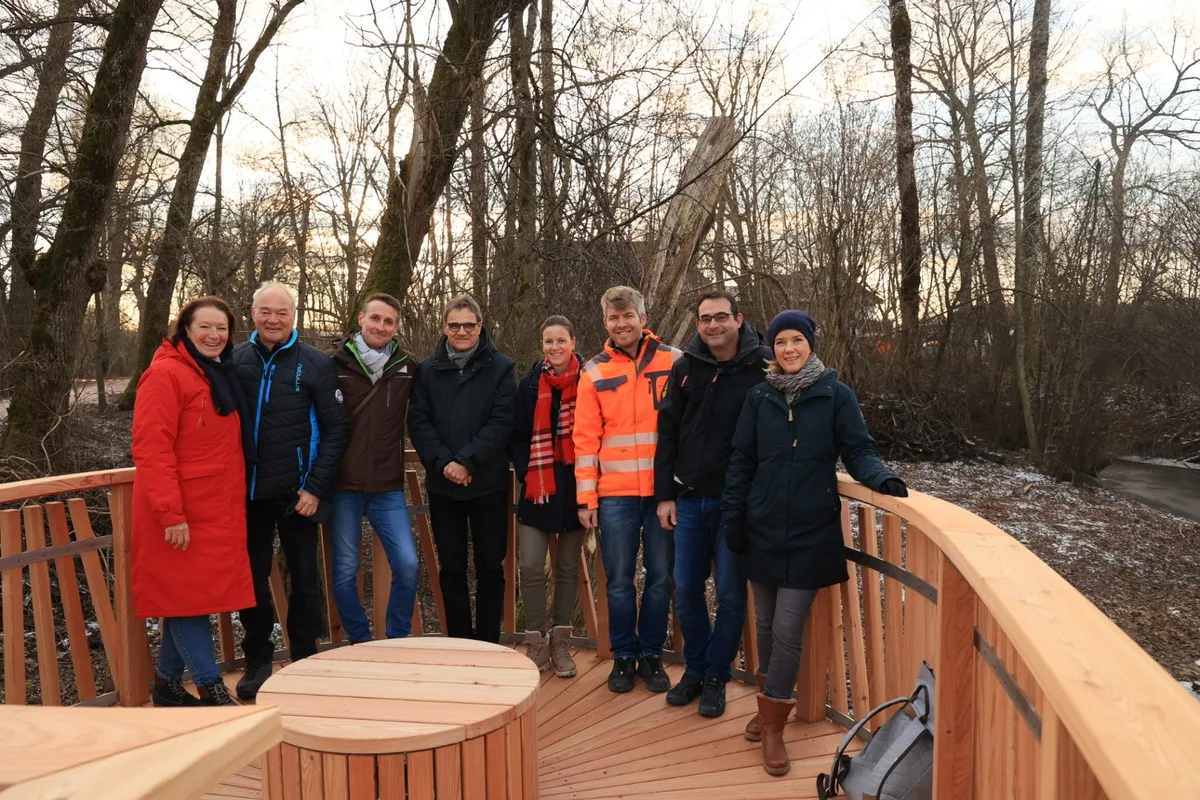 Eine Gruppe von Leuten steht auf einem neuen Holzsteg.